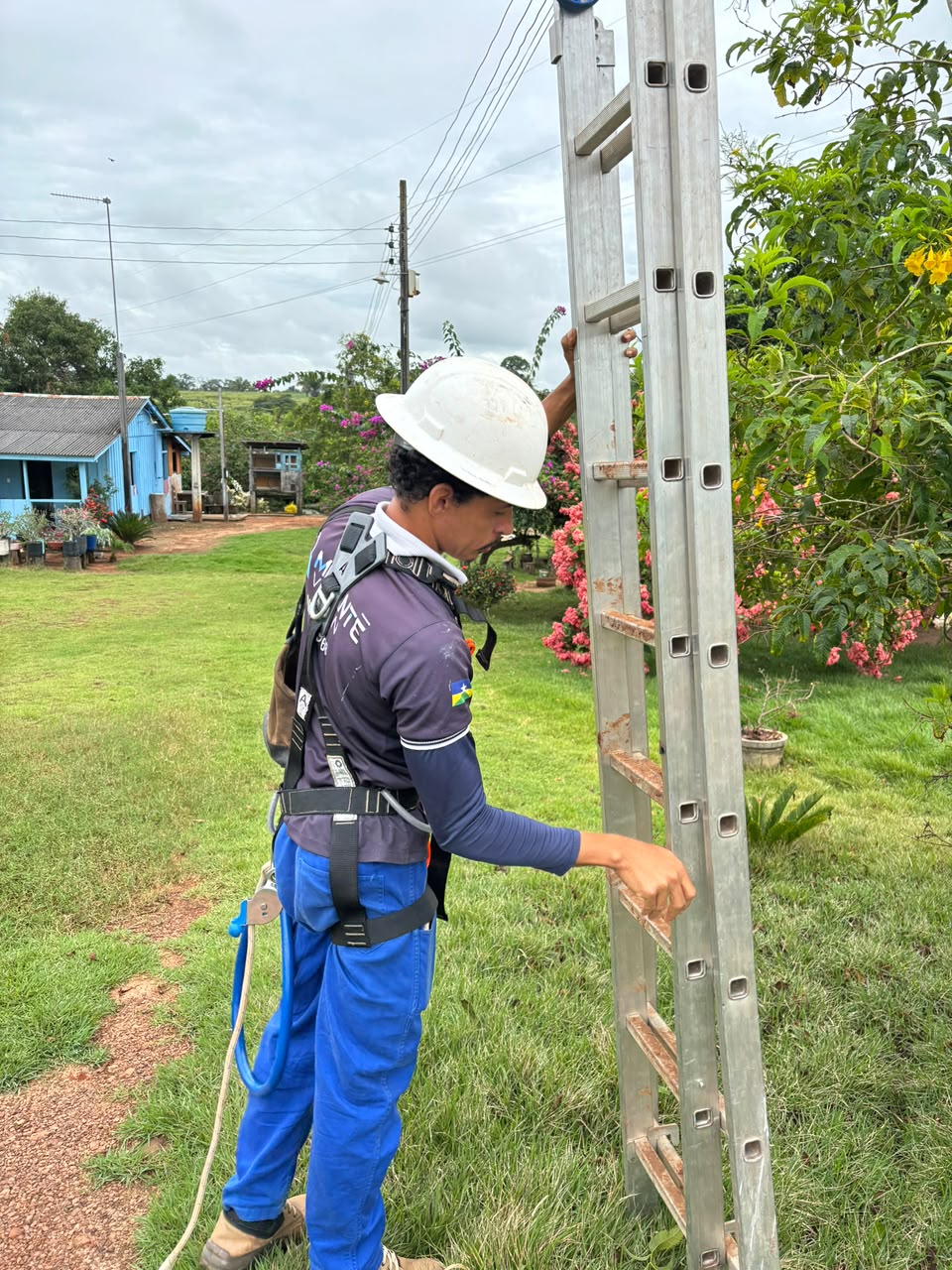 Técnico da Climax Soluções com capacete e cinto de segurança posicionando escada para instalação em campo